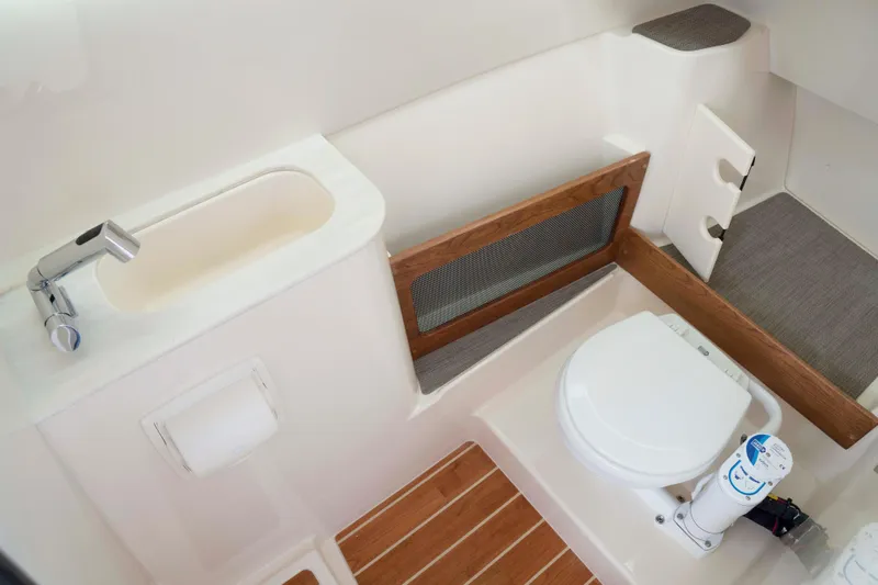 Slide: The Image of 2026 Grady-White Freedom 285 boat bathroom with sink, toilet, and wooden accents. - 2