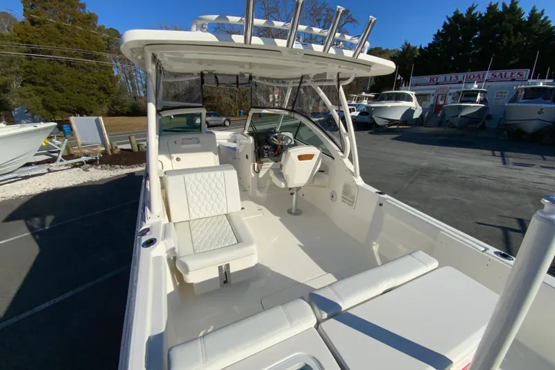Slide: The Image of 2026 Pursuit DC 246 Dual Console boat interior with seating and helm, parked outdoors. - 11