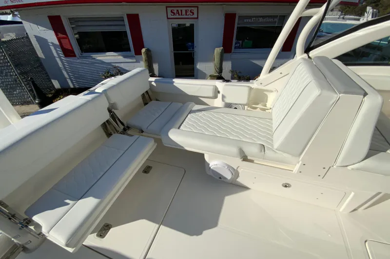 Slide: The Image of 2026 Pursuit DC 246 Dual Console boat interior with white seating and sales office background. - 17