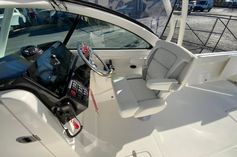 Slide: The Image of 2026 Pursuit DC 246 Dual Console boat interior with steering wheel and captain's chair. - 21