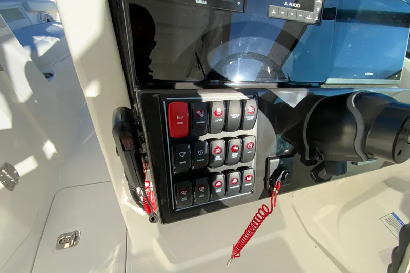 Slide: The Image of Control panel of 2026 Pursuit DC 246 Dual Console boat with switches and steering wheel. - 23