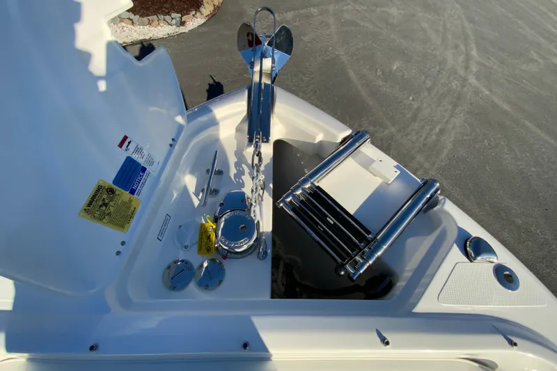 Slide: The Image of 2026 Pursuit DC 246 Dual Console boat anchor compartment with ladder and safety labels. - 28