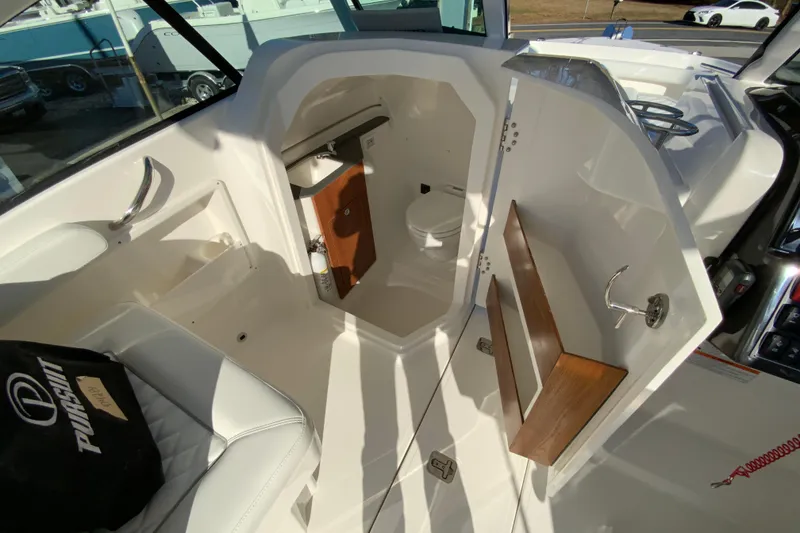 Slide: The Image of 2026 Pursuit DC 246 Dual Console boat interior with open storage compartment and seating. - 35