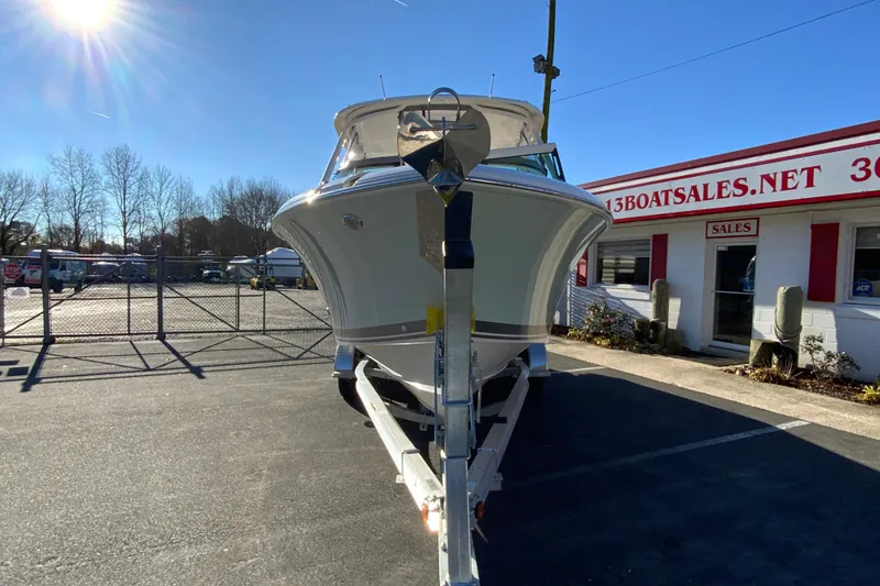 Slide: The Image of 2026 Pursuit DC 246 Dual Console boat on trailer at dealership under sunny sky. - 4