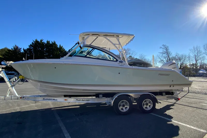 Slide: The Image of 2026 Pursuit DC 246 Dual Console boat on trailer under clear blue sky. - 6