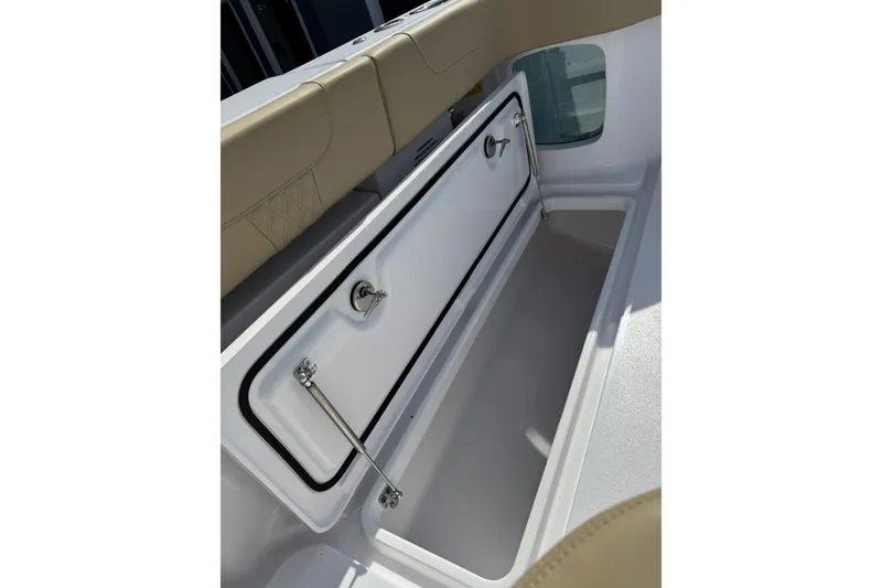 Slide: The Image of 2026 Phenom 37 Center Console storage compartment with beige seating and secure latch. - 18
