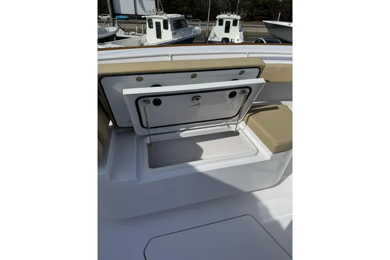 Slide: The Image of Open storage compartment on 2026 Phenom 37 Center Console boat, featuring beige seating. - 23