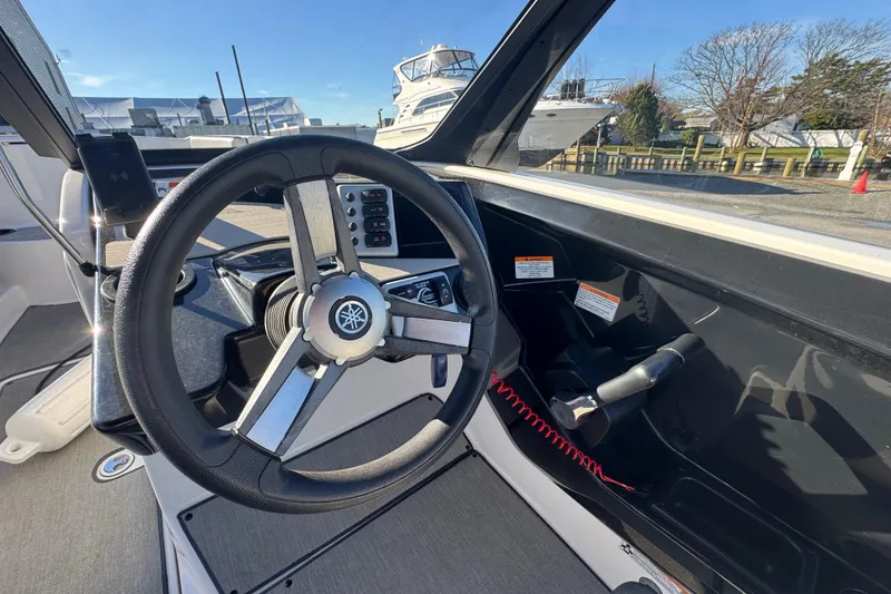 Slide: The Image of 2023 Yamaha Boats AR220 steering wheel and dashboard in a marina setting. - 10
