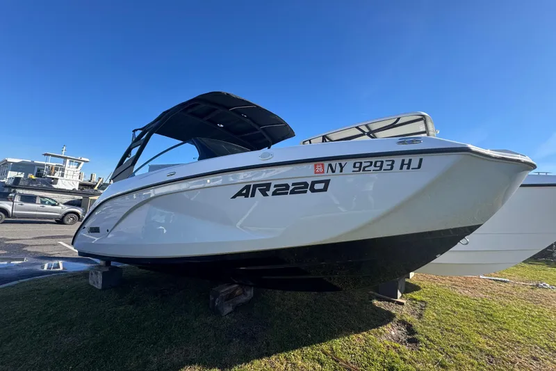 Slide: The Image of 2023 Yamaha Boats AR220 on display, white hull, parked on grass. - 5