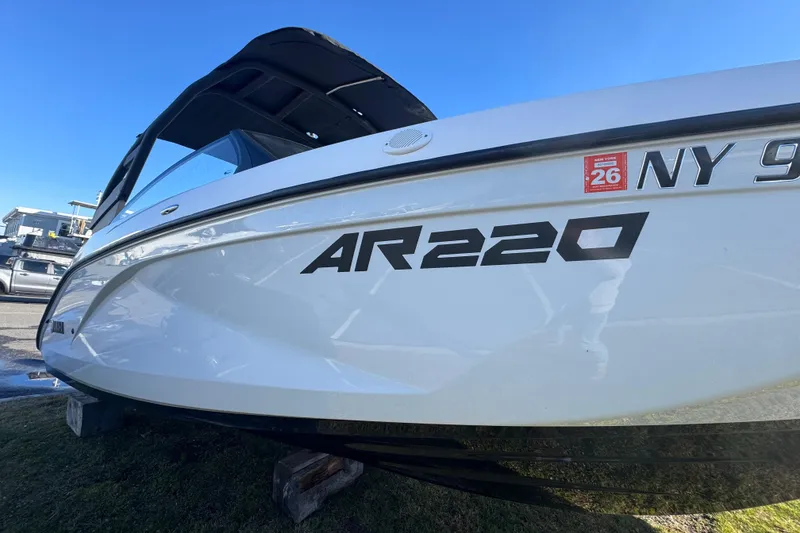 Slide: The Image of 2023 Yamaha Boats AR220, white hull, docked on grass, clear blue sky background. - 7