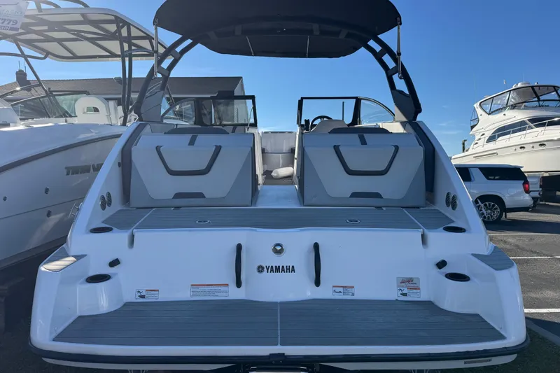 Slide: The Image of 2023 Yamaha Boats AR220, rear view, docked with sleek design and spacious seating. - 8