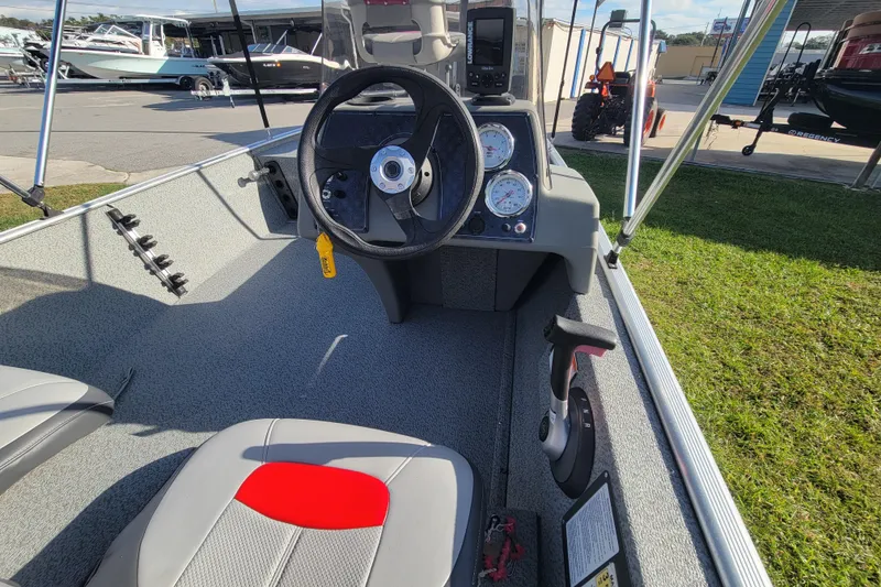 Slide: The Image of 2016 Tracker Pro 160 boat interior with steering wheel and gauges, parked outdoors. - 13