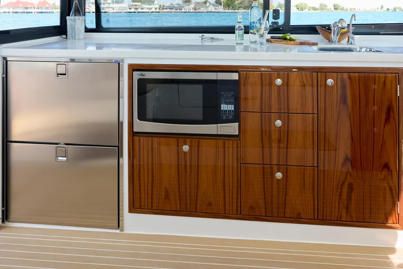 Slide: The Image of Luxury yacht kitchen with wood cabinetry, stainless steel appliances, and ocean view. MJM 47X, 2026 model. - 10
