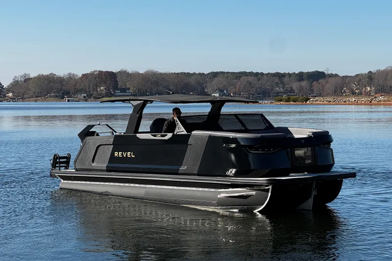 Slide: The Image of Revel RS25L 2026 pontoon boat on a serene lake with clear blue skies. - 6