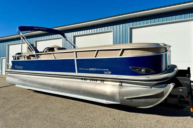 The Image of 2012 Regency Sun Tracker Party Barge pontoon boat parked outside a blue building. - 0