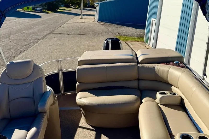 Slide: The Image of 2012 Regency Sun Tracker Party Barge with beige seating, parked near a blue building. - 46