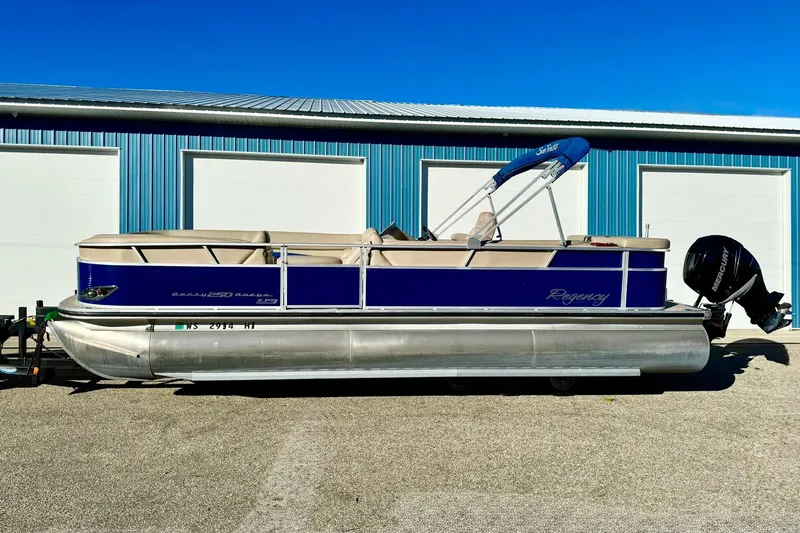 Slide: The Image of 2012 Regency Sun Tracker Party Barge pontoon boat with blue and beige design, parked outdoors. - 53