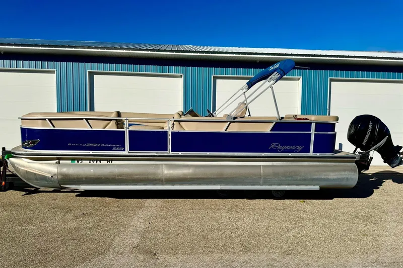 Slide: The Image of 2012 Regency Sun Tracker Party Barge pontoon boat with blue and beige design, parked outdoors. - 55