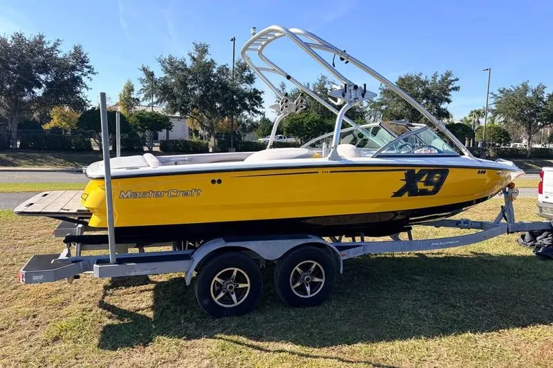 Slide: The Image of 2006 MasterCraft X-9 boat in bright yellow on a trailer, parked on grass. - 9