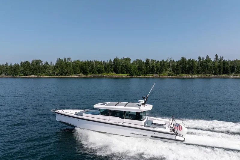 Slide: The Image of 2026 Axopar 37 XC cruising on a serene lake with forested shoreline. - 12