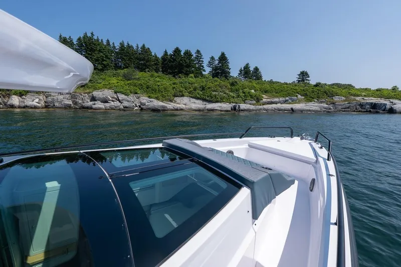 Slide: The Image of 2026 Axopar 37 XC boat cruising near rocky shoreline and lush greenery. - 25