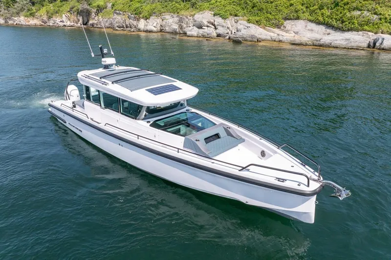 Slide: The Image of 2026 Axopar 37 XC cruising on clear waters near rocky shoreline. - 3