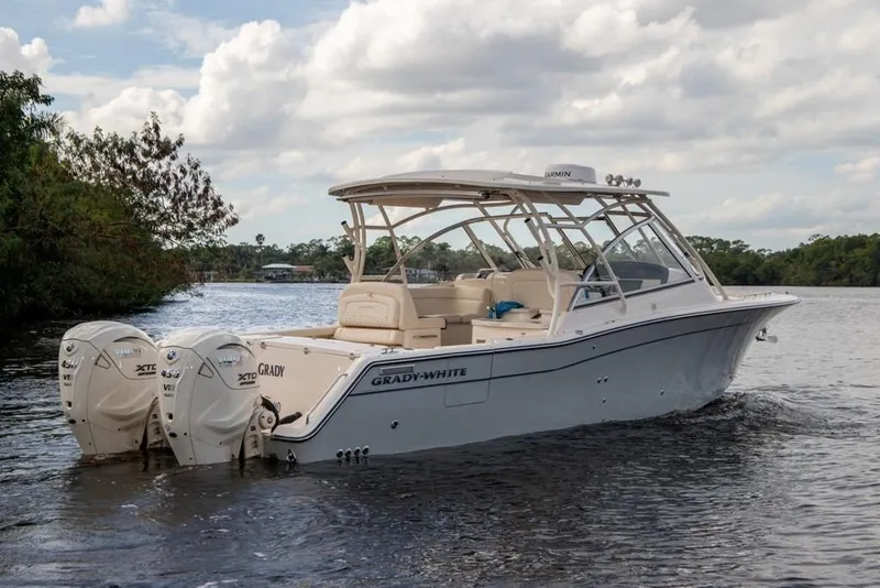 Slide: The Image of 2024 Grady-White Freedom 335 boat on a calm river, featuring dual outboard engines. - 11