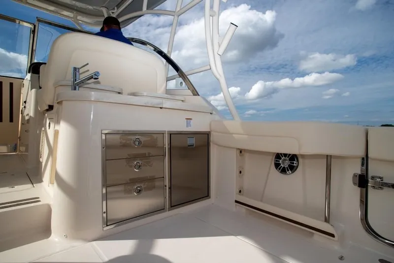 Slide: The Image of 2024 Grady-White Freedom 335 boat interior with seating, storage, and sink under a blue sky. - 16