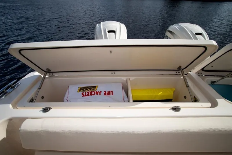 Slide: The Image of 2024 Grady-White Freedom 335 boat storage compartment with life jackets, open on calm water. - 45