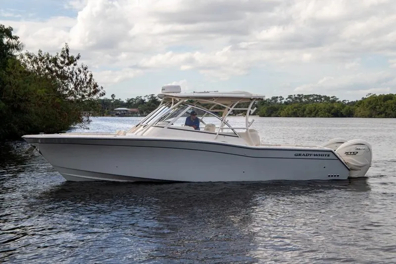 Slide: The Image of 2024 Grady-White Freedom 335 boat cruising on a calm river under a cloudy sky. - 8