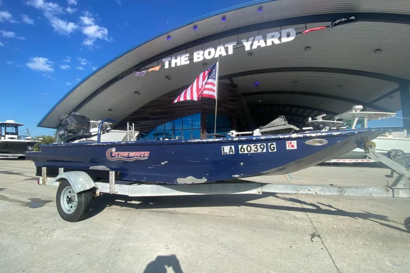 Slide: The Image of 2014 Cottonmouth 18x60 boat on trailer at The Boat Yard, American flag displayed. - 10
