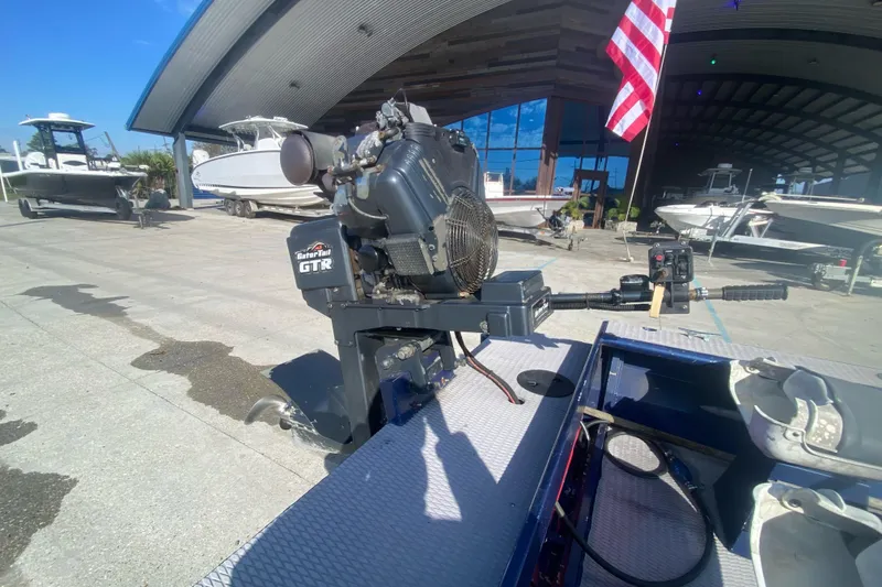 Slide: The Image of Boat motor on a 2014 Cottonmouth 18x60, parked near a marina with other boats. - 12