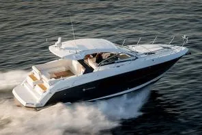 Slide: The Image of 2021 Cruisers Yachts 390 Express Coupe on a serene lake under clear blue skies. - 2