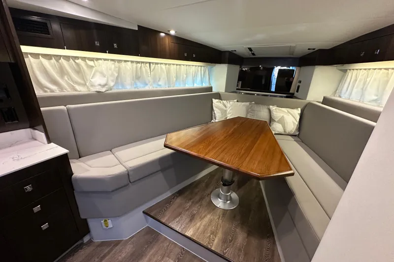 Slide: The Image of 2021 Cruisers Yachts 390 Express Coupe interior with white seating and wooden table. - 37