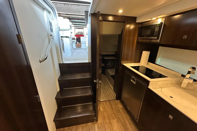 Slide: The Image of Interior of 2021 Cruisers Yachts 390 Express Coupe, featuring modern kitchen and stairs. - 58