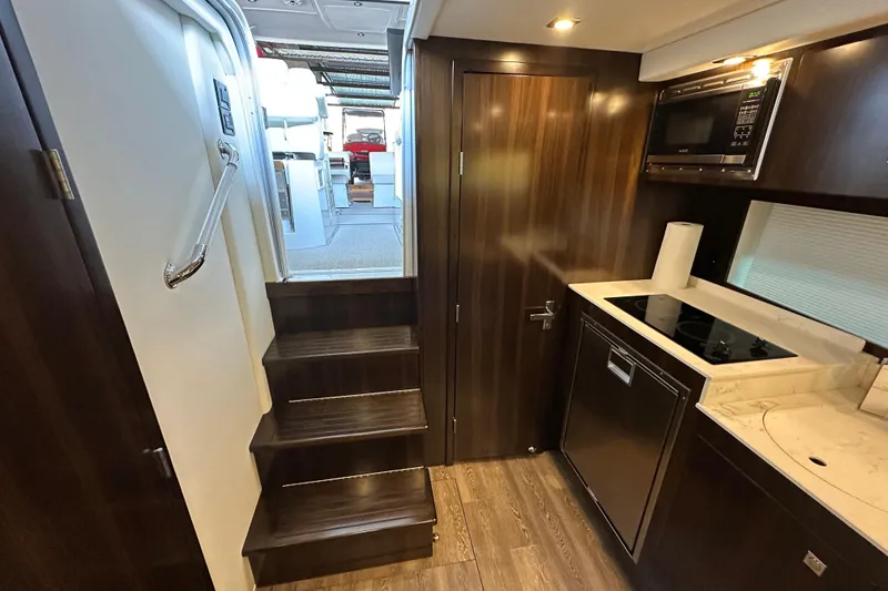 Slide: The Image of Interior of 2021 Cruisers Yachts 390 Express Coupe, featuring modern kitchen and stairs. - 59