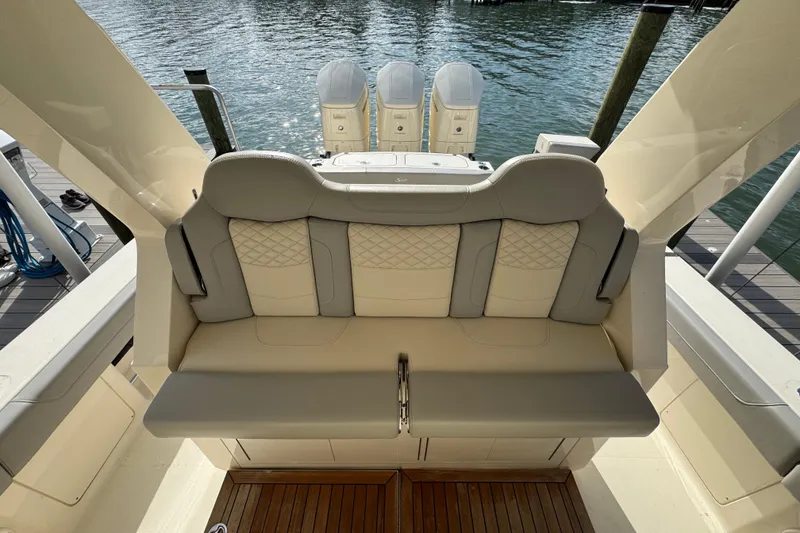 Slide: The Image of 2024 Scout 425 LXF luxury boat seating with triple outboard engines, docked by the water. - 22
