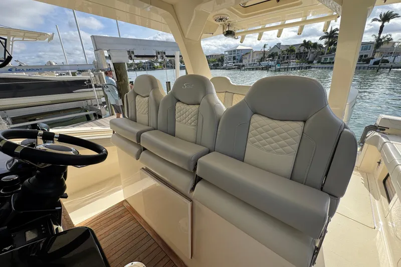 Slide: The Image of 2024 Scout 425 LXF boat interior with luxurious seating and steering wheel, dockside view. - 24