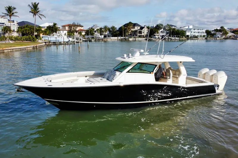 Slide: The Image of 2024 Scout 425 LXF boat on calm water, surrounded by waterfront homes and palm trees. - 3