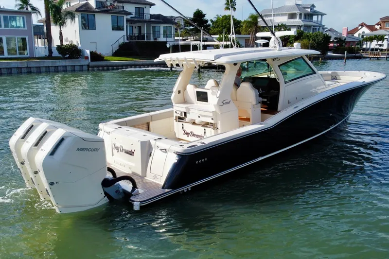 Slide: The Image of 2024 Scout 425 LXF boat with triple Mercury engines on a scenic waterfront. - 5