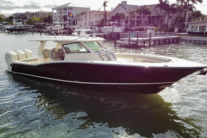 Slide: The Image of 2024 Scout 425 LXF luxury boat docked in a scenic waterfront setting. - 7