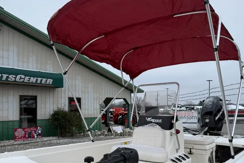 Slide: The Image of 2012 Mako Pro Skiff 17 CC boat with red canopy at a sports center. - 4
