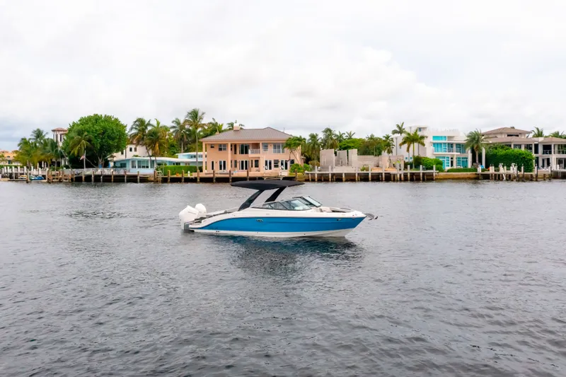 Slide: The Image of 2026 Sea Ray SLX 280 Outboard on calm water near coastal homes. - 1