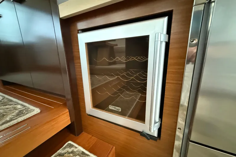 Slide: The Image of Built-in wine cooler on 2016 Tiara Yachts 50 Coupe, featuring wooden cabinetry and stainless steel accents. - 15