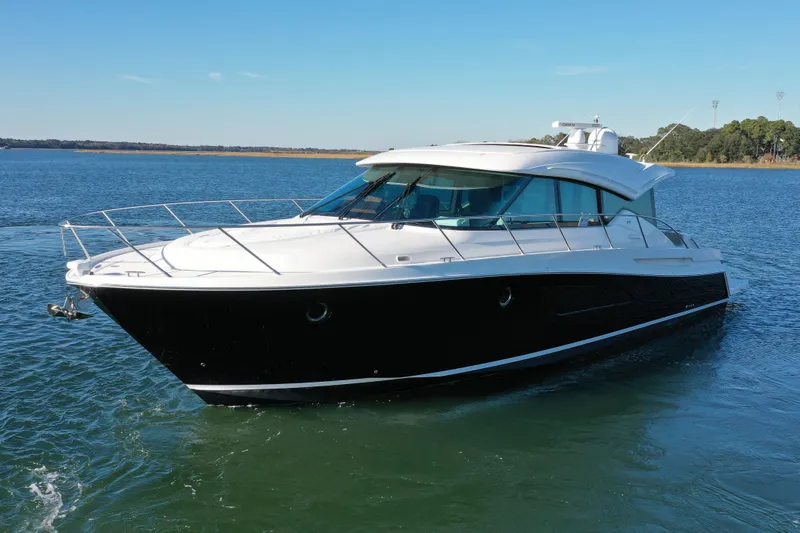 Slide: The Image of 2016 Tiara Yachts 50 Coupe cruising on a serene lake under a clear blue sky. - 3