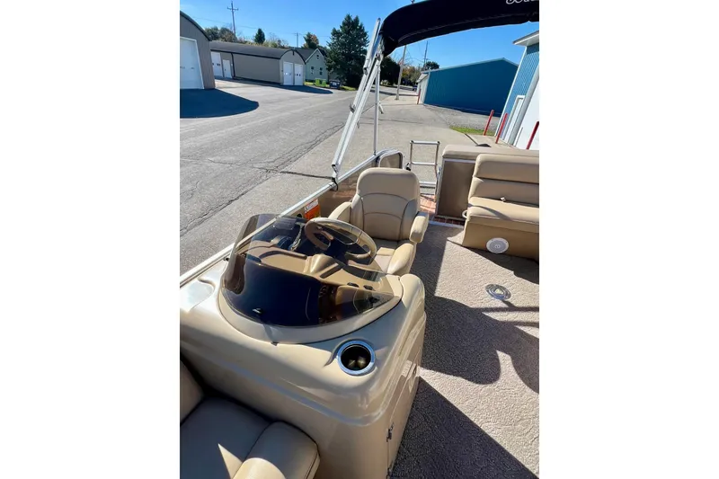 Slide: The Image of 2013 South Bay 417 CR pontoon boat with beige seating and canopy, parked near blue building. - 37