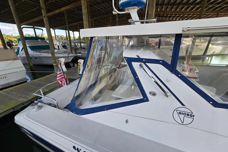 Slide: The Image of 1993 Giorgi 46 boat docked in a marina, featuring a sleek design and American flag. - 85