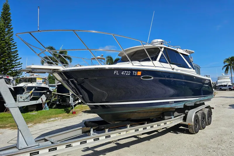 Slide: The Image of 2024 Cutwater C-248 Coupe boat on trailer, parked outdoors under clear blue sky. - 2
