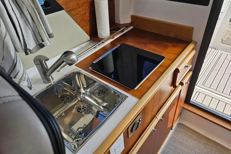 Slide: The Image of 2024 Cutwater C-248 Coupe interior kitchen with sink, stove, and wooden cabinetry. - 25