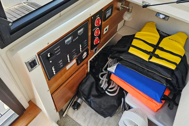 Slide: The Image of 2024 Cutwater C-248 Coupe interior with control panel, life jackets, and storage items. - 30